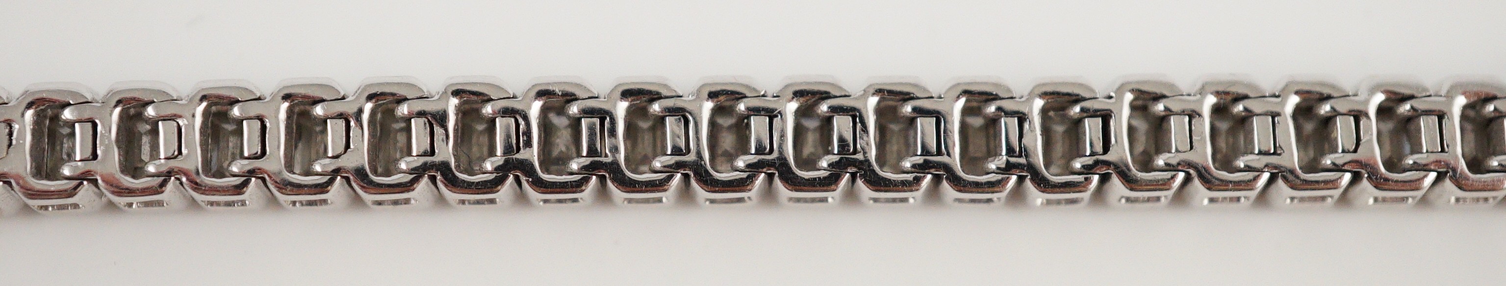 A modern 18ct white gold and emerald cut diamond set line bracelet